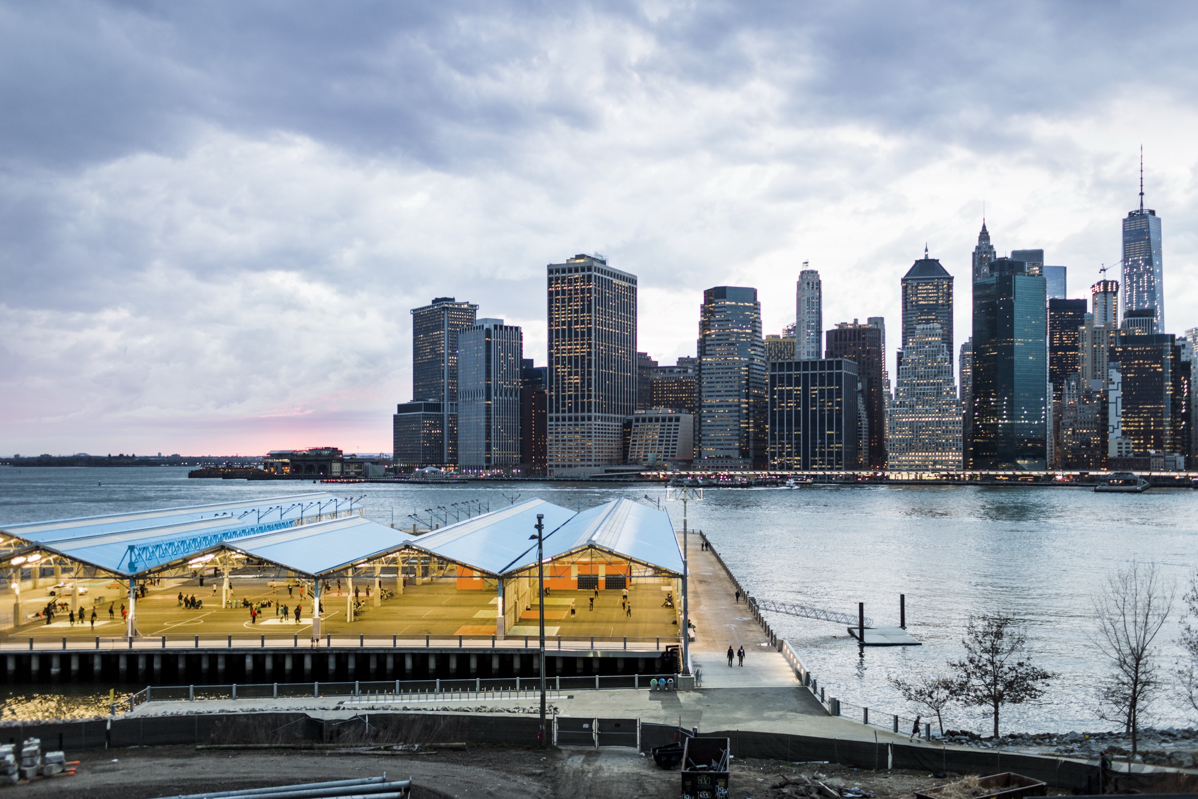 Lawns and the harborfront promenade of Brooklyn Bridge Park with lower Manhattan across the East River