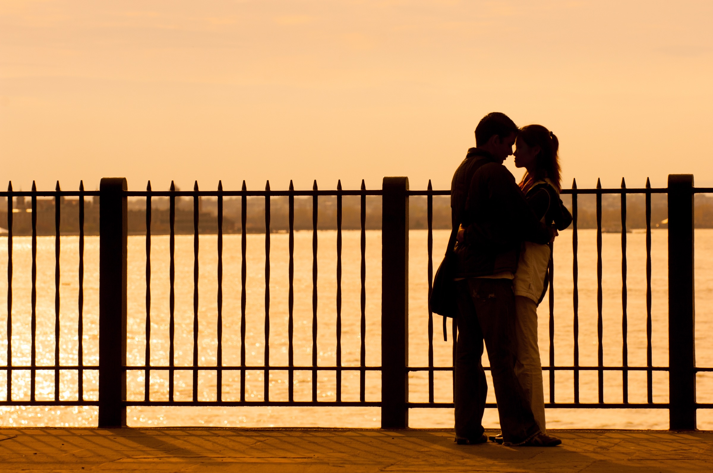 The lower Manhattan skyline and harbor seen across benches and railings on the Brooklyn Heights Promenade