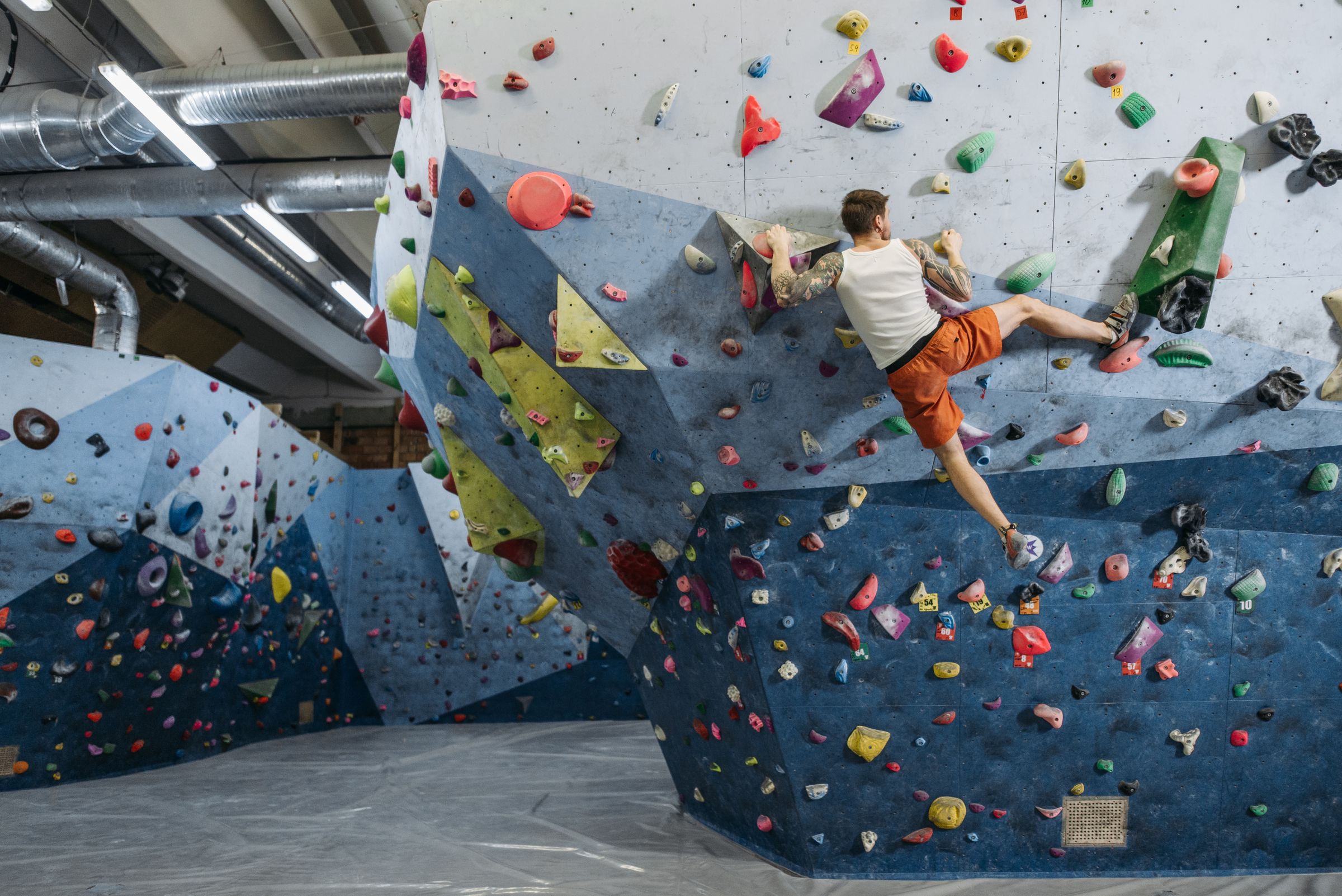 Climbers on the angled walls of a bouldering gym