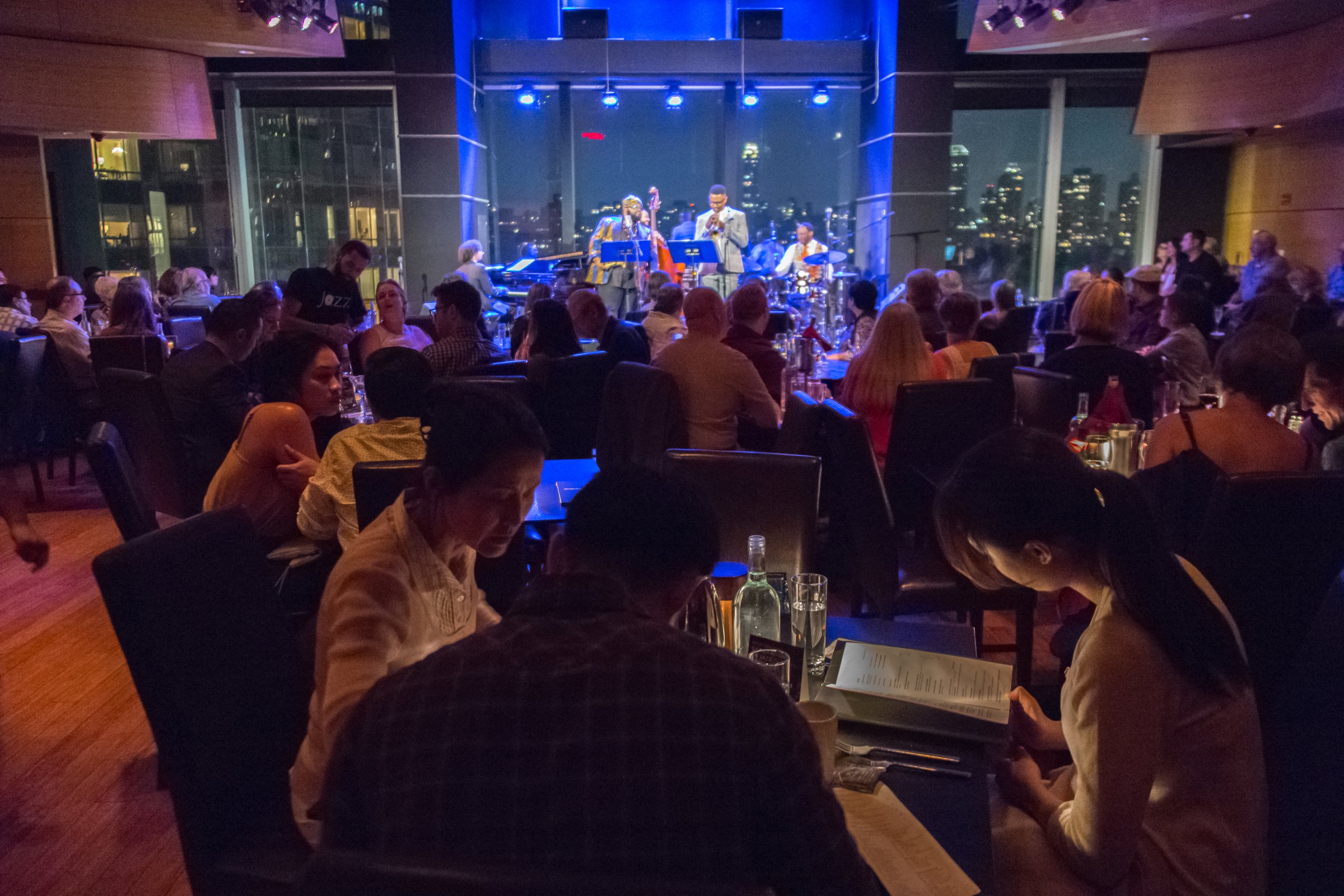 A full house at Dizzy's Club, the band lit blue against the windows over Columbus Circle