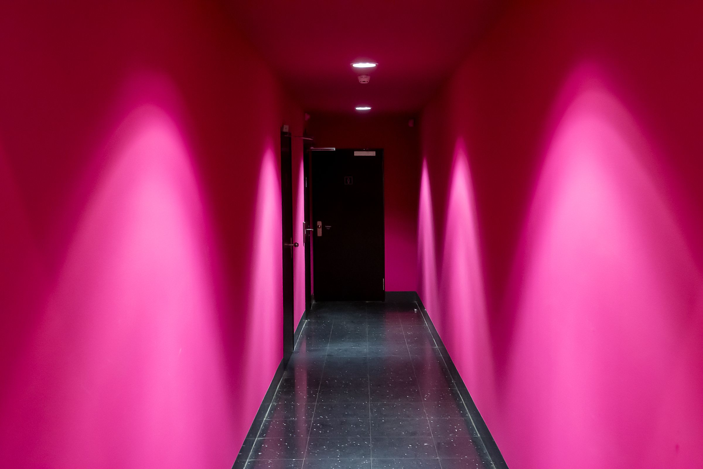 A corridor washed in magenta light