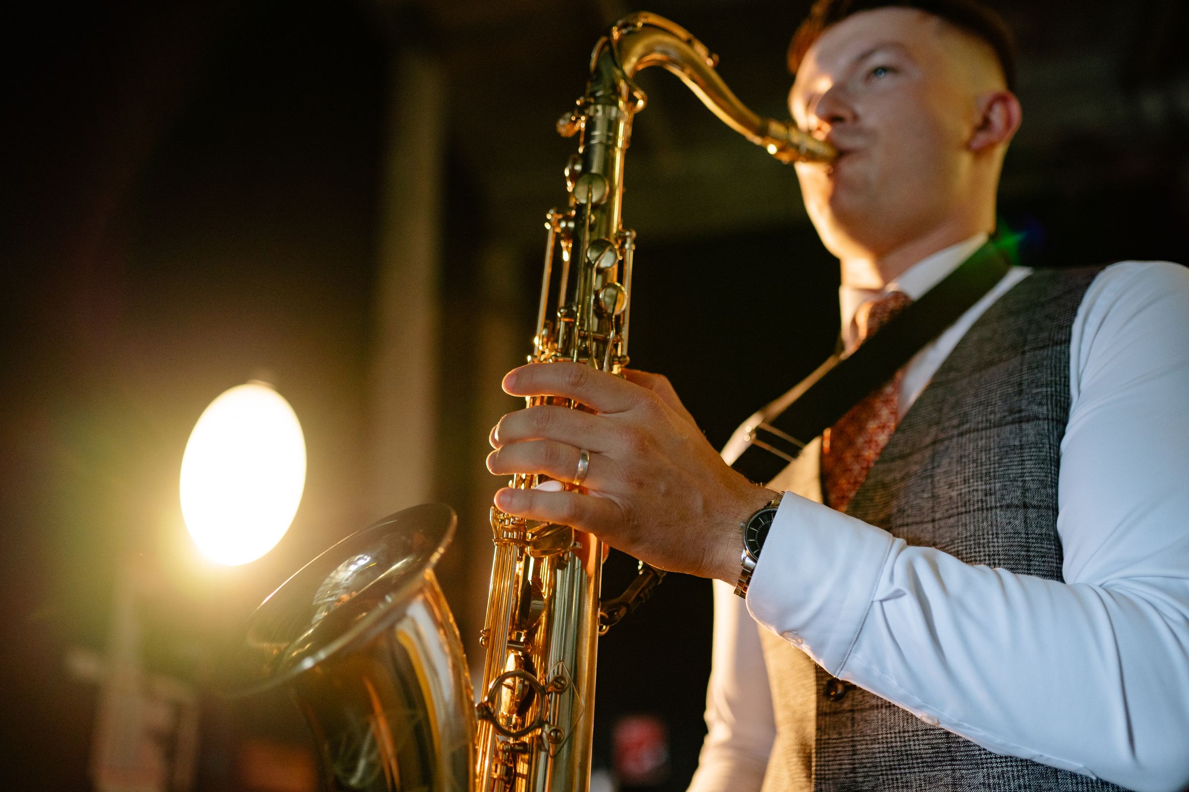 A saxophonist playing in warm stage light