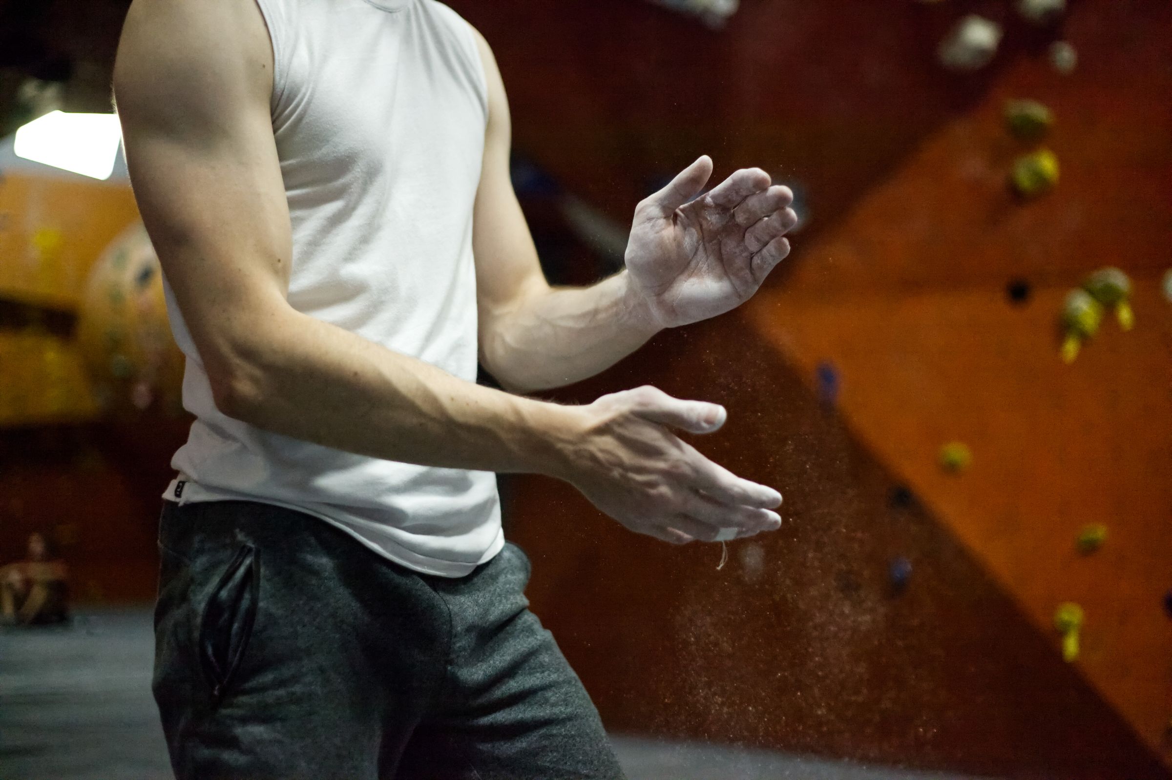 A climber chalking up in front of a bouldering wall