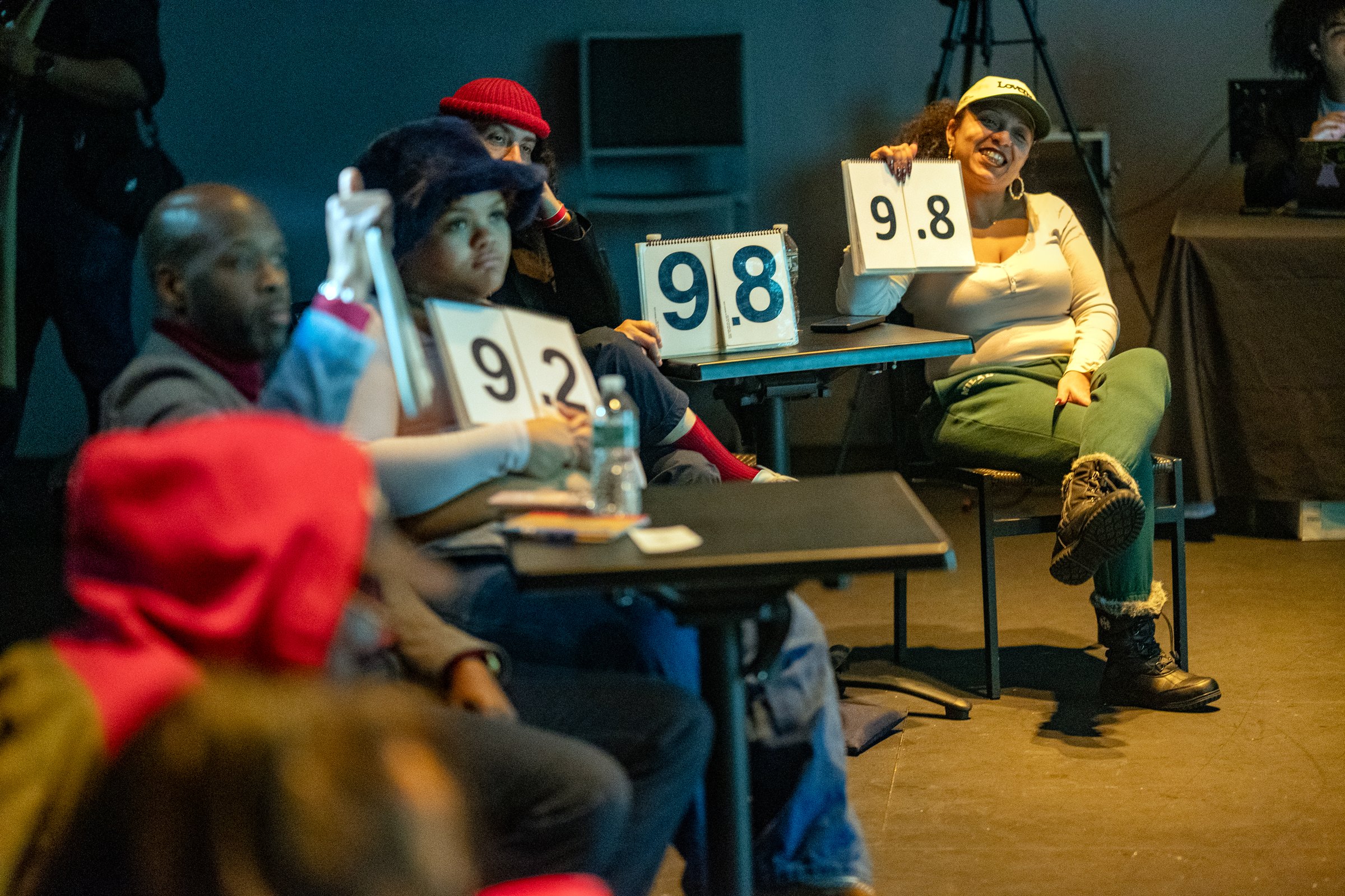 Audience judges holding up scorecards, a 9.8 among them, at the Nuyorican Poets Cafe Grand Slam