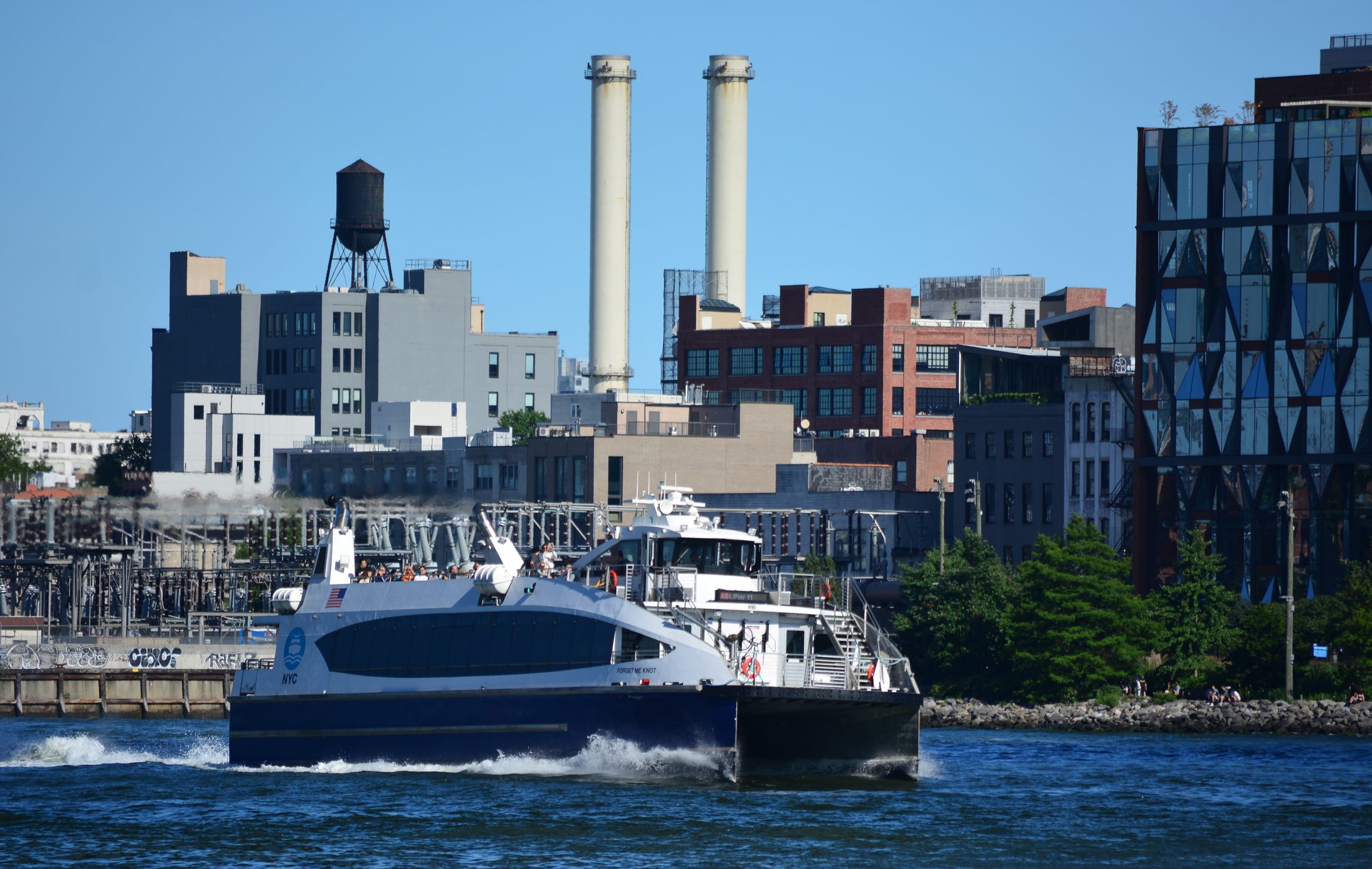 An NYC Ferry boat crossing the East River just east of the Manhattan Bridge