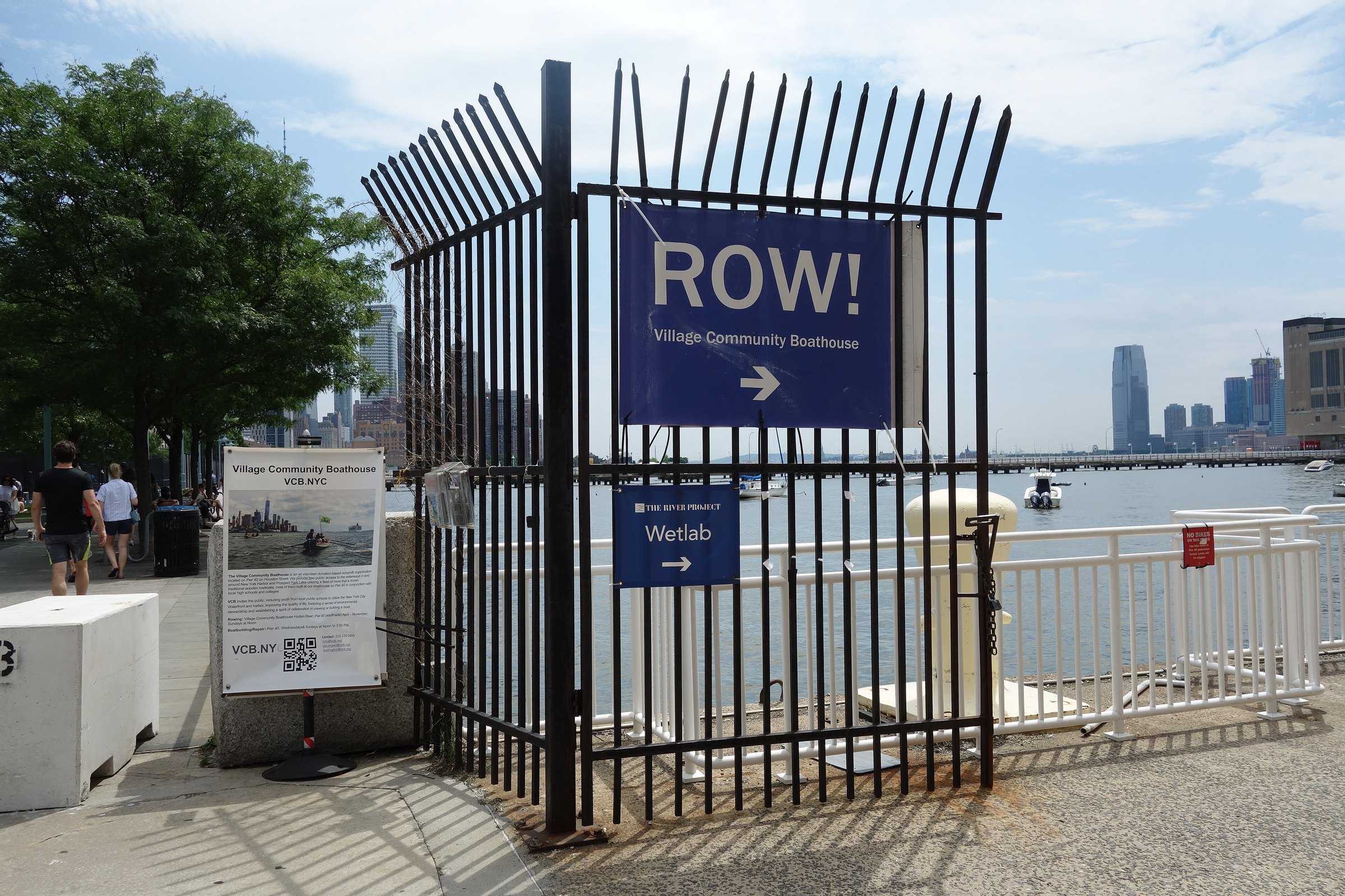 The 'ROW!' sign for the Village Community Boathouse on Pier 40, the Hudson and Jersey City beyond