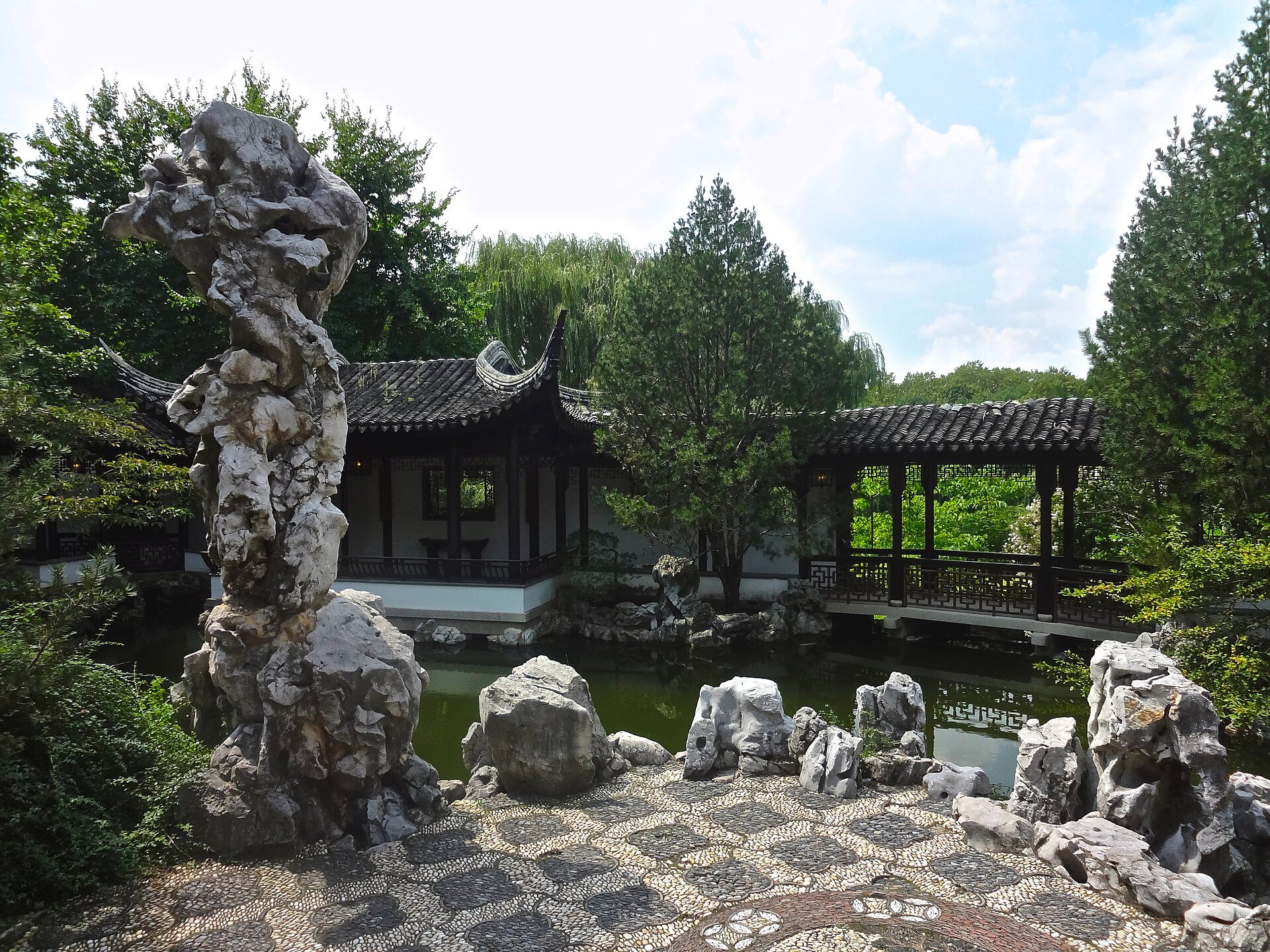 A tall scholar's rock, a pavilion and a pond in the walled New York Chinese Scholar's Garden on Staten Island