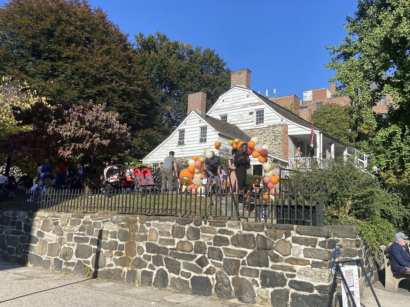 The white clapboard Dyckman Farmhouse above a fieldstone wall on Broadway in Inwood