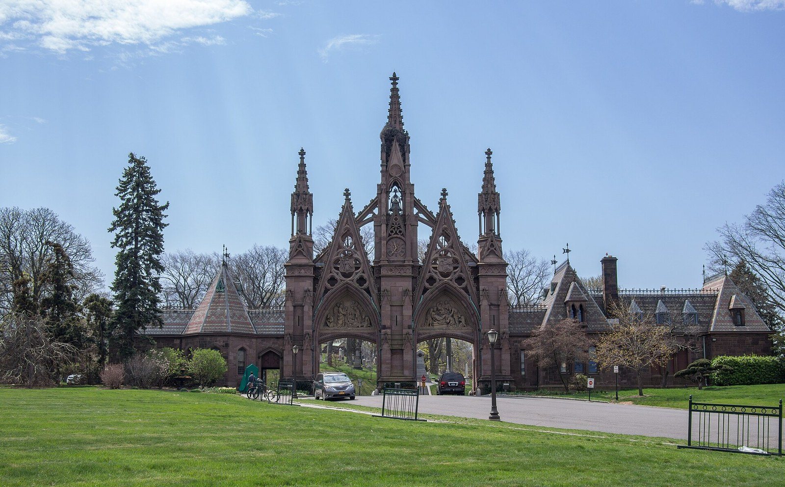 The Gothic Revival main gate of Green-Wood Cemetery rising over a green lawn in spring