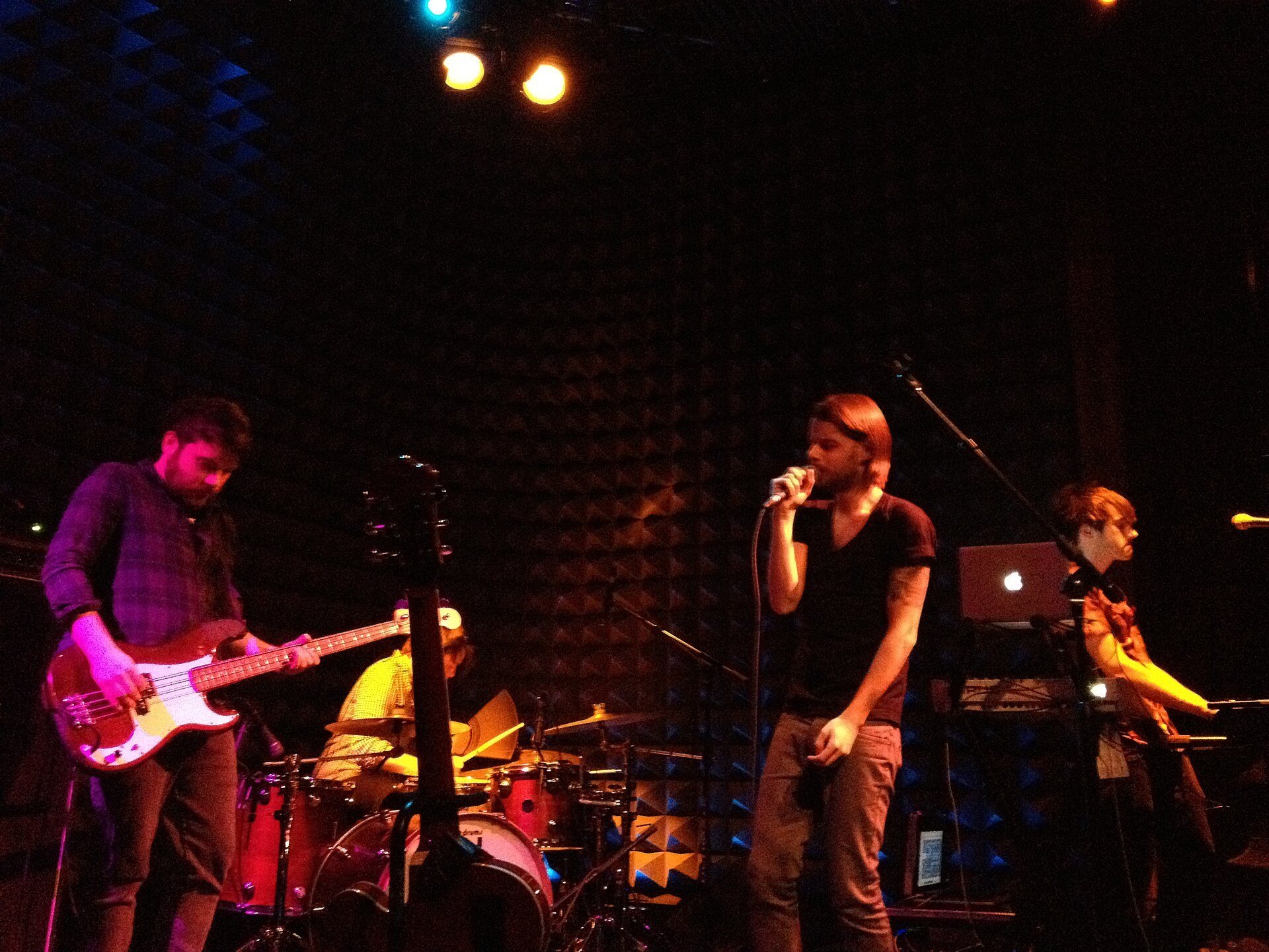 A band performing under red stage lights at Joe's Pub, seen from the audience