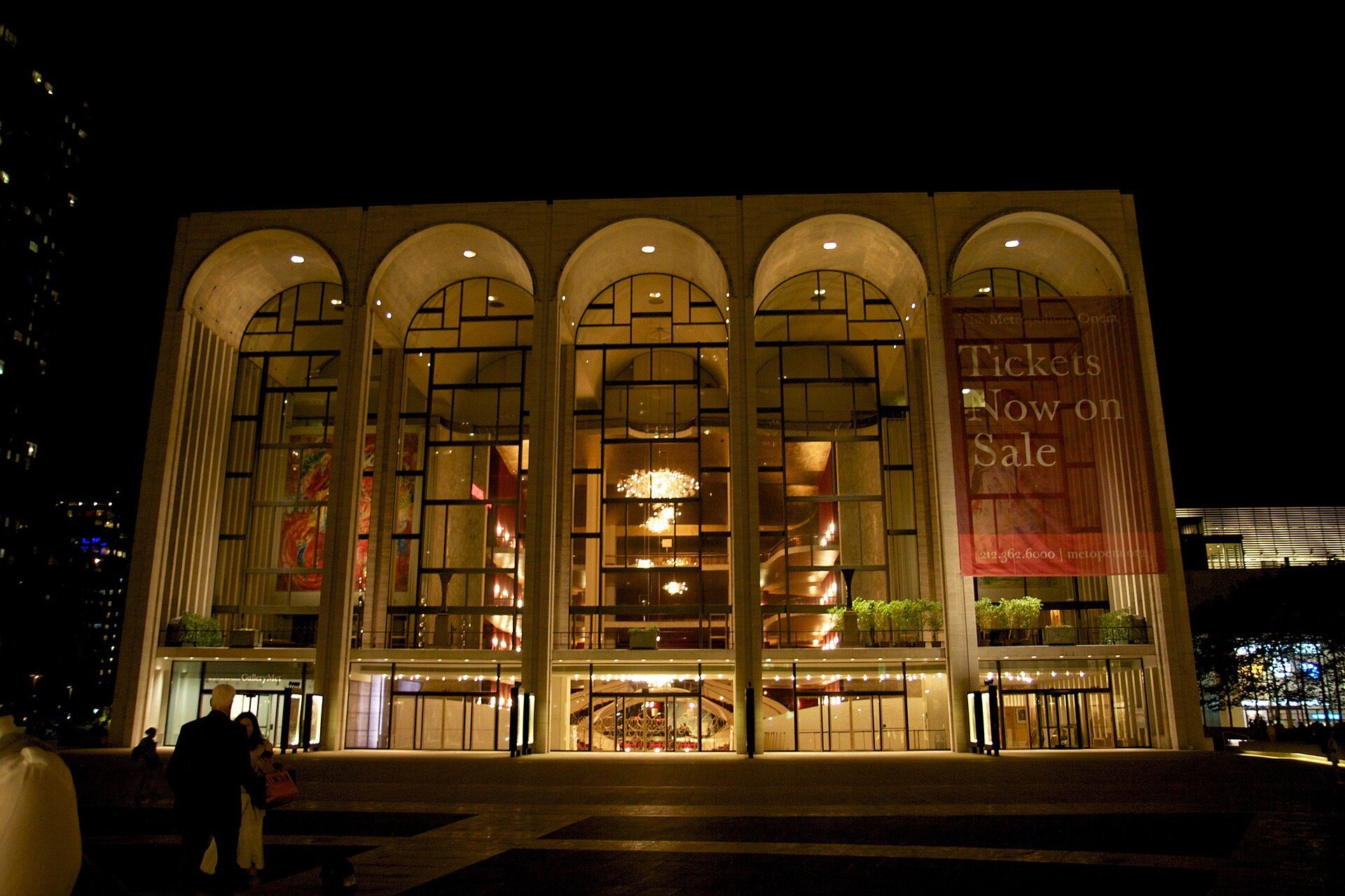 The Metropolitan Opera House at Lincoln Center at night, its arched windows lit from within