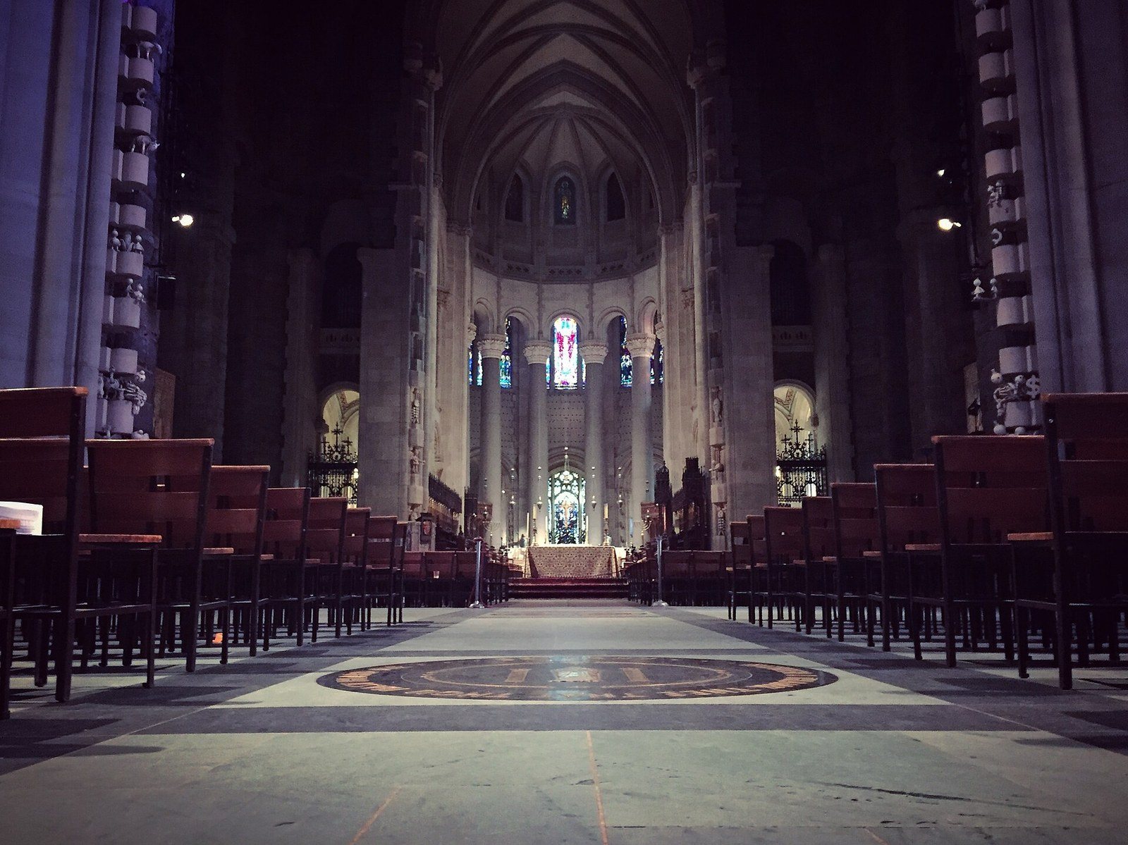 The long nave of the Cathedral of St. John the Divine seen from floor level, rows of chairs leading to the altar