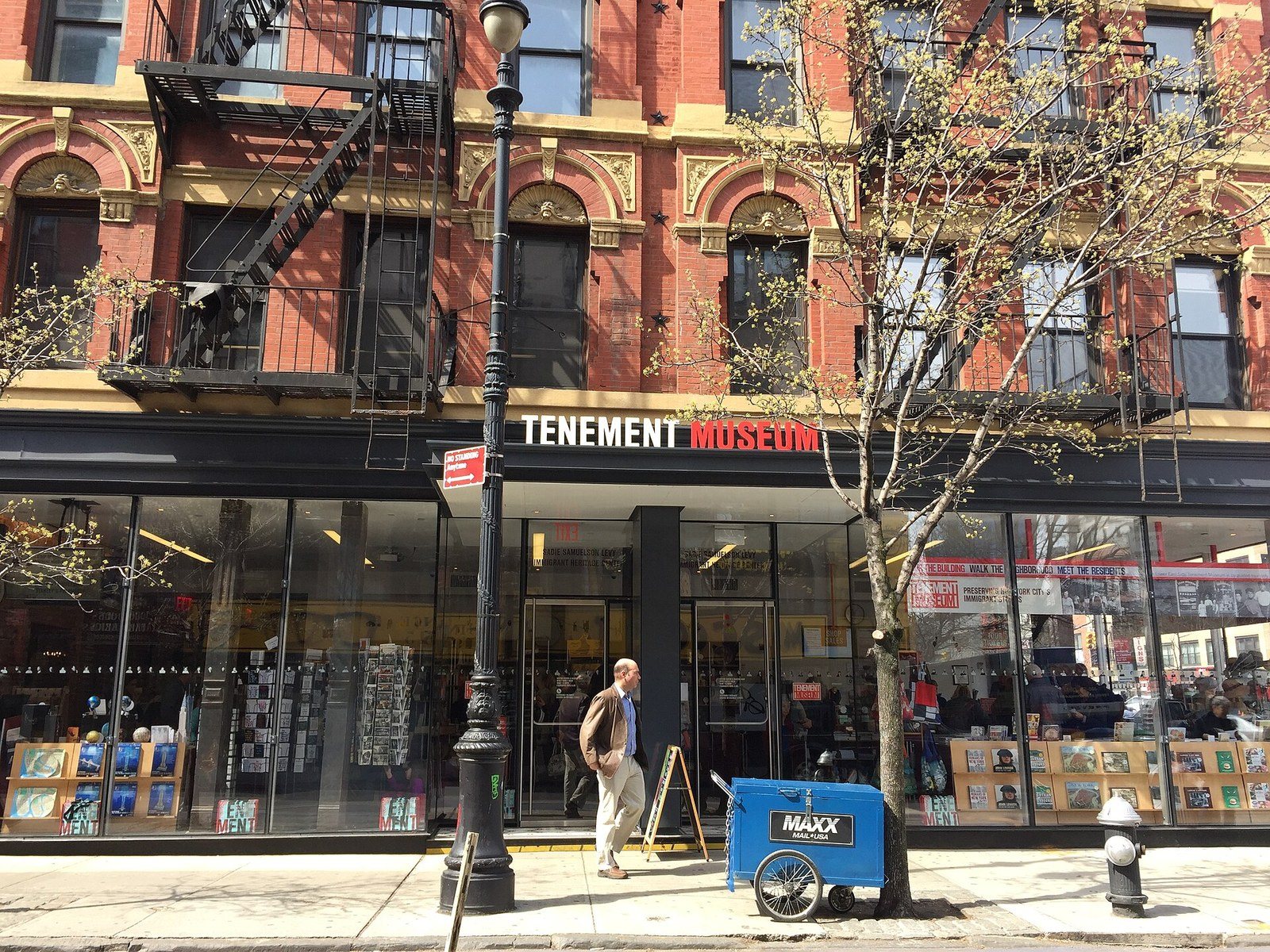 The Tenement Museum's storefront and sign on Orchard Street, beneath a red-brick tenement with fire escapes