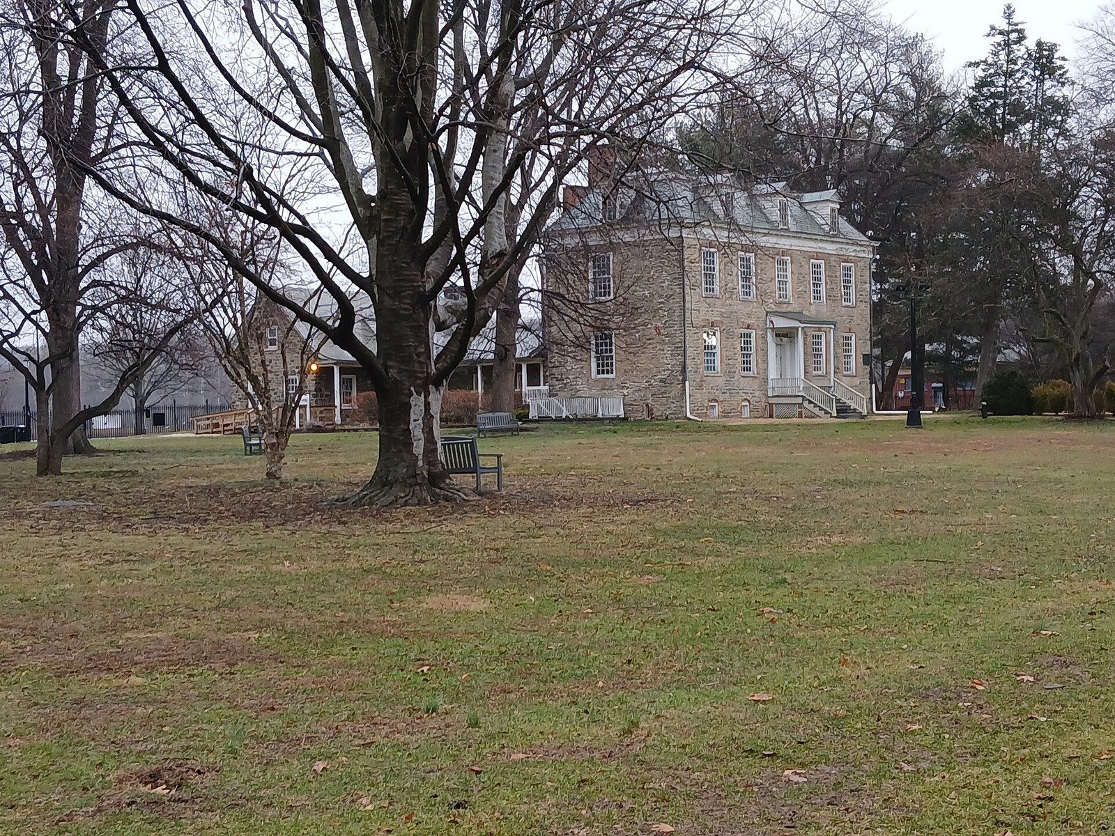 The fieldstone Van Cortlandt House seen across a lawn under bare trees in Van Cortlandt Park