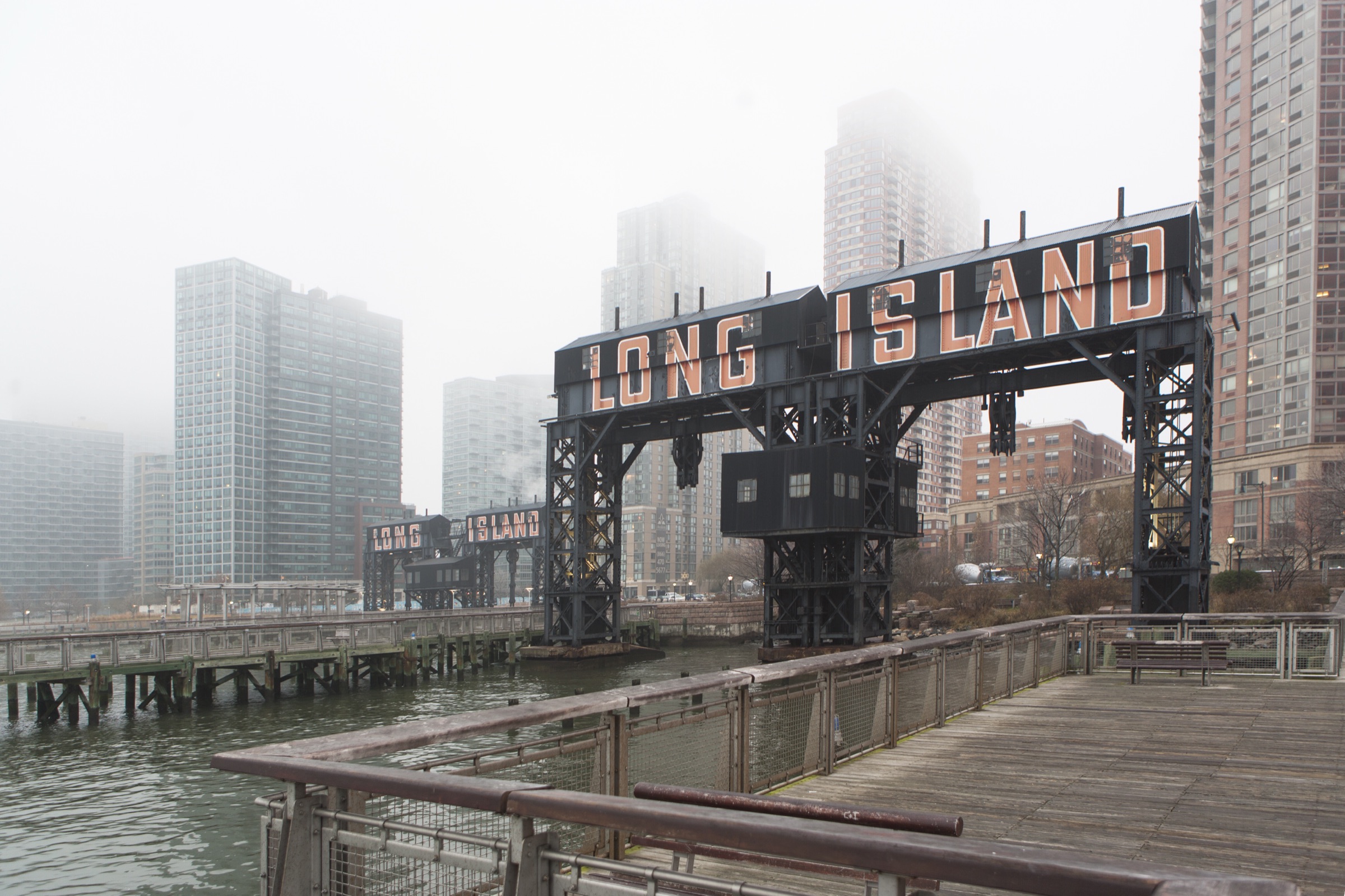 The restored black transfer gantries at Gantry Plaza State Park with the midtown Manhattan skyline across the East River