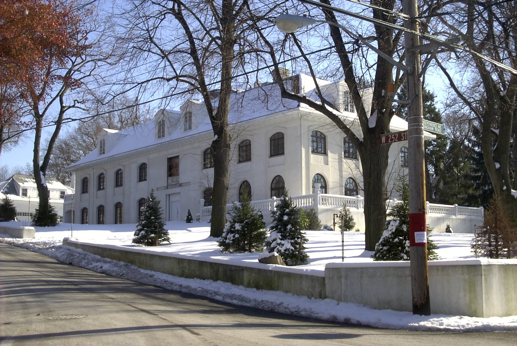 A white Georgian house on Independence Avenue in Riverdale, known as the JFK House, behind snowy hedges