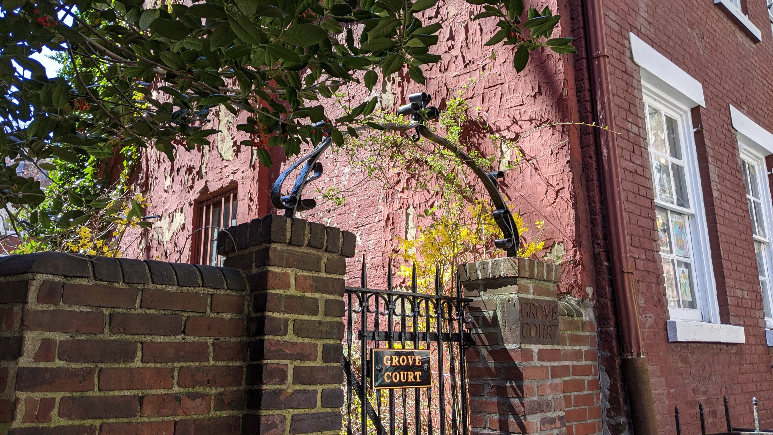 Brick rowhouses of Grove Court seen through its iron gate, with a small shared garden