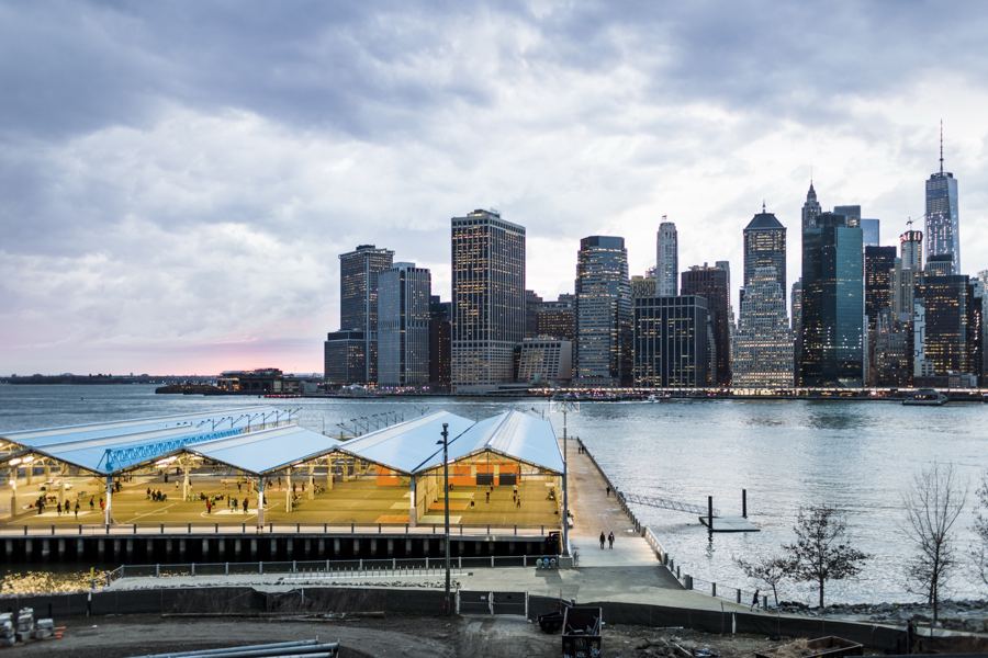 Lawns and the harborfront promenade of Brooklyn Bridge Park with lower Manhattan across the East River