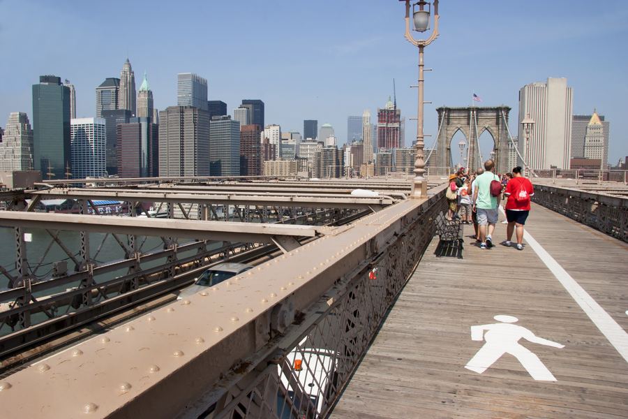 The Brooklyn Bridge's wooden walkway, steel cables and granite Gothic tower against the sky