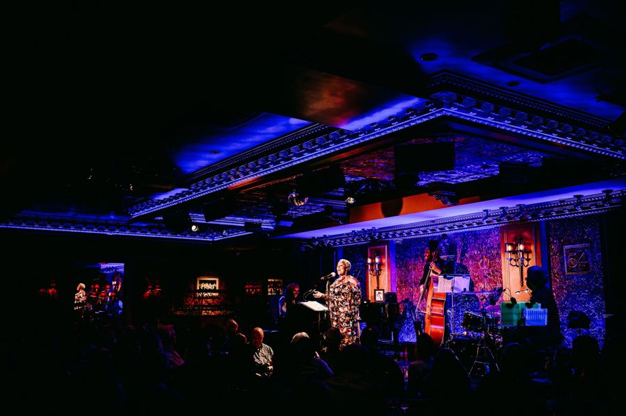 Lillias White singing on the 54 Below stage under blue and violet light, with her band behind her