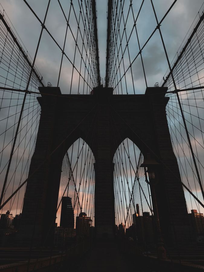 The Brooklyn Bridge's Gothic arches silhouetted against the morning sky