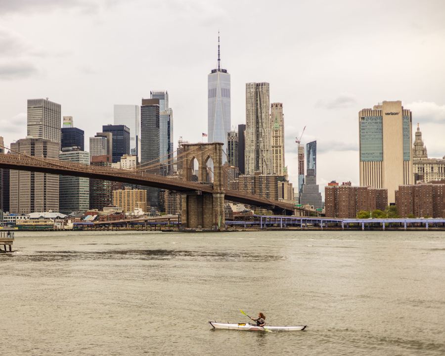 A kayaker on the East River below the Brooklyn Bridge, with Lower Manhattan beyond