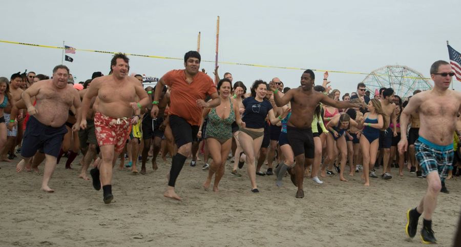 Plungers charging across the sand toward the ocean at Coney Island on New Year's Day, the Wonder Wheel behind