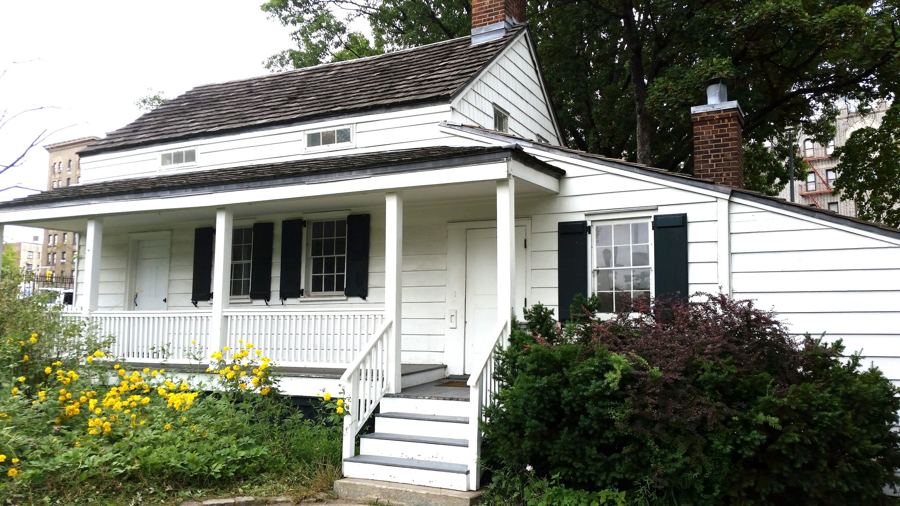 The white clapboard Edgar Allan Poe Cottage in Poe Park on the Grand Concourse, its porch edged with flowers