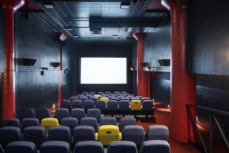 Looking down the aisle to the screen, past bright yellow seats, in a Film Forum theater