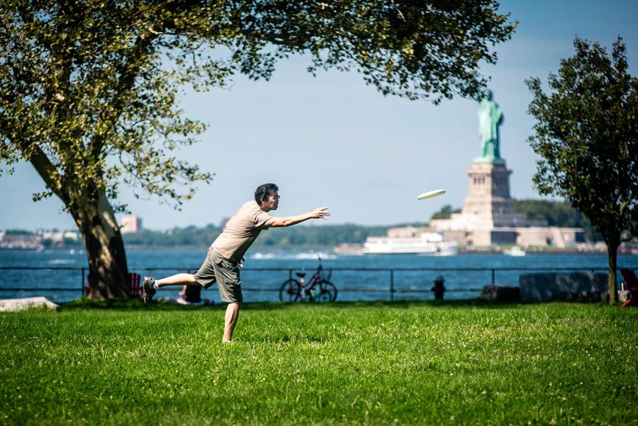 A frisbee game on the lawn at Picnic Point, Governors Island, with the Statue of Liberty behind