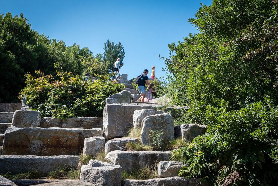 Visitors scrambling up the granite slabs of Outlook Hill on Governors Island