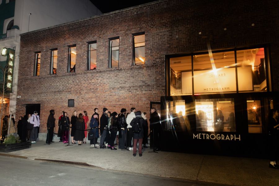 A crowd lined up at night outside Metrograph's glowing windows