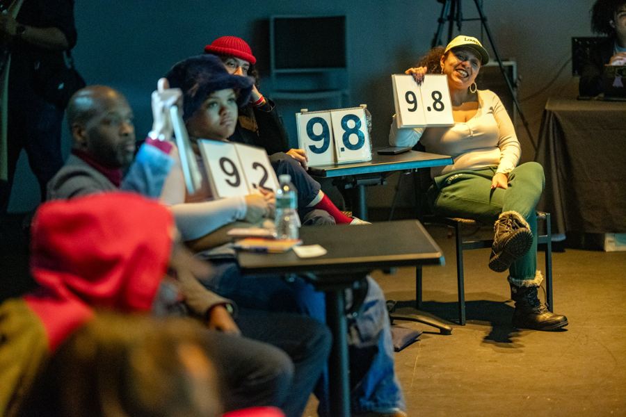 Audience judges holding up scorecards, a 9.8 among them, at the Nuyorican Poets Cafe Grand Slam