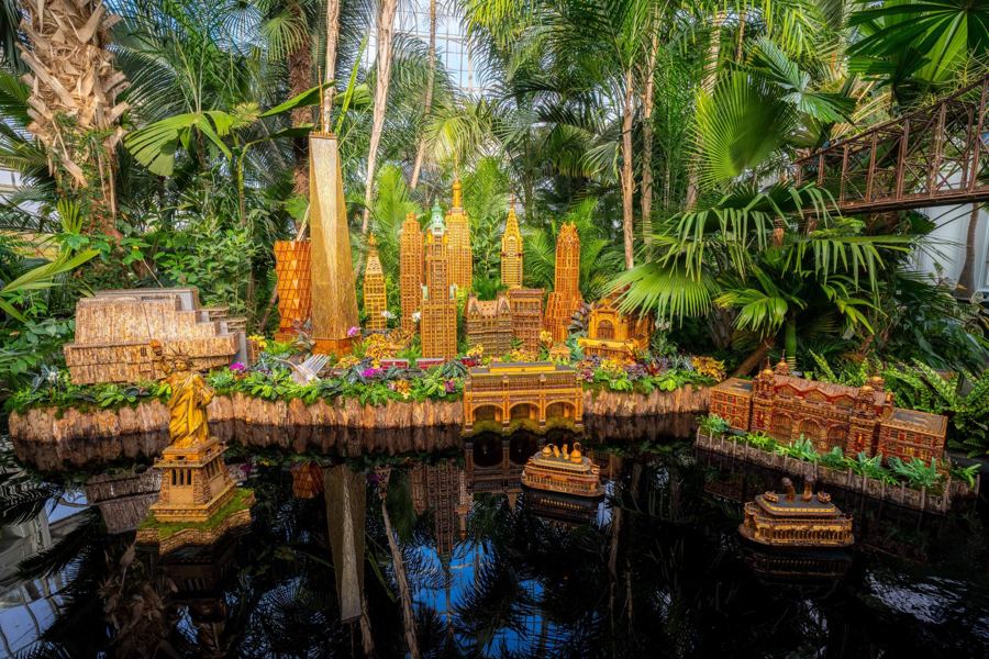 A New York skyline built from bark, seeds and leaves over a reflecting pool in the Haupt Conservatory at the Holiday Train Show