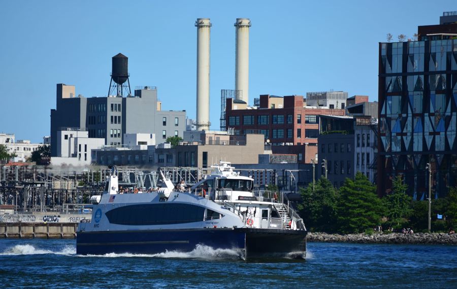 An NYC Ferry boat crossing the East River just east of the Manhattan Bridge
