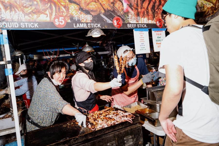 Vendors working the grills under the market's tents