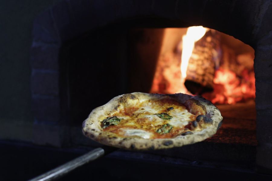 A pizza coming out of a wood-fired oven at the market