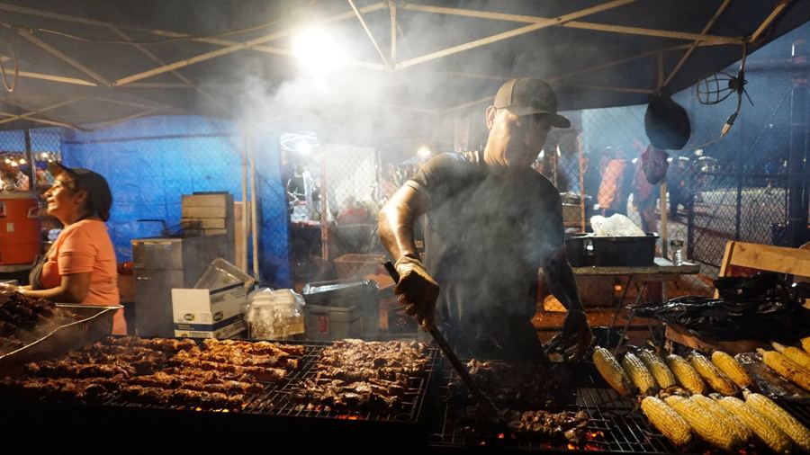 Smoke rising from a grill stall at night