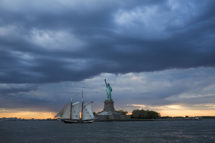 Pioneer by the Statue of Liberty under a stormy evening sky