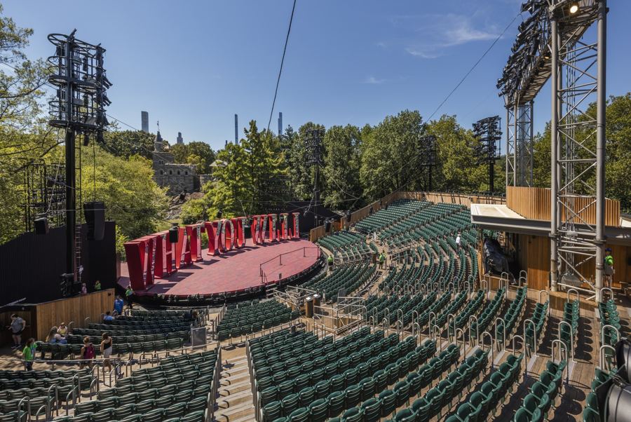 Rows of green seats wrapping the Delacorte's red stage under its lighting towers