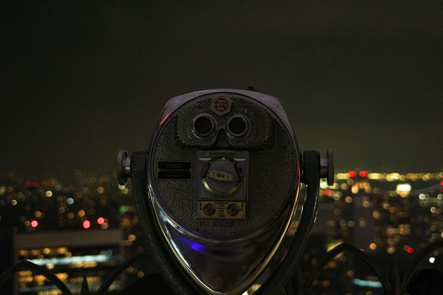A coin-operated viewer above city lights at night