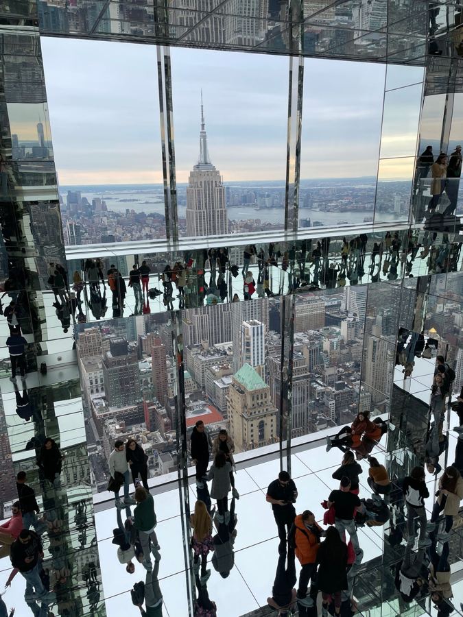 Visitors in SUMMIT's mirrored rooms, with Midtown towers in the glass