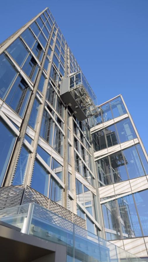 Looking up at SUMMIT One Vanderbilt's glass Ascent elevator on the side of the tower against a blue sky