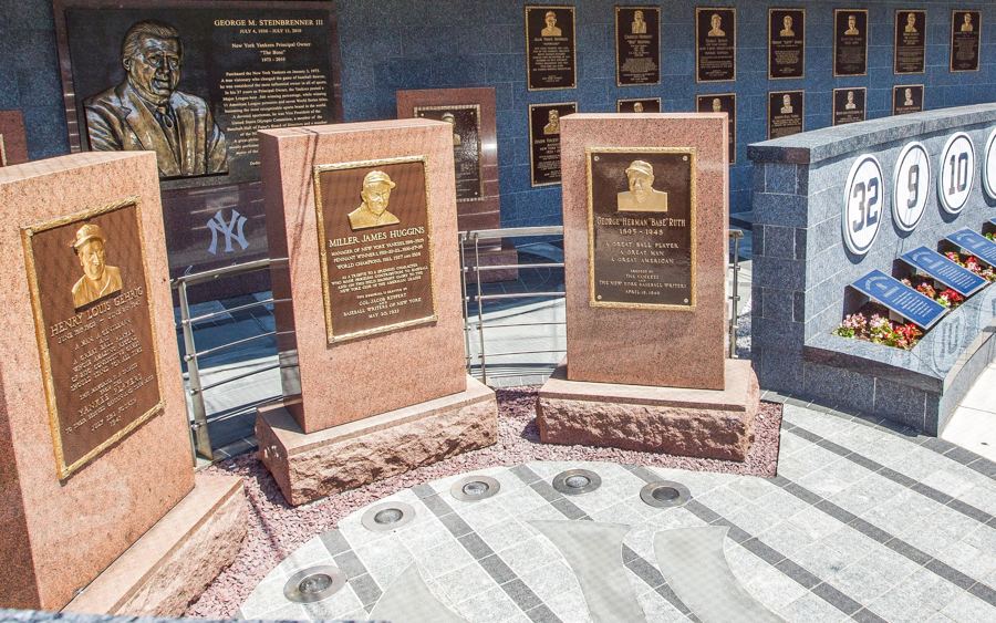 Red granite monuments and bronze plaques in Monument Park beyond the outfield wall
