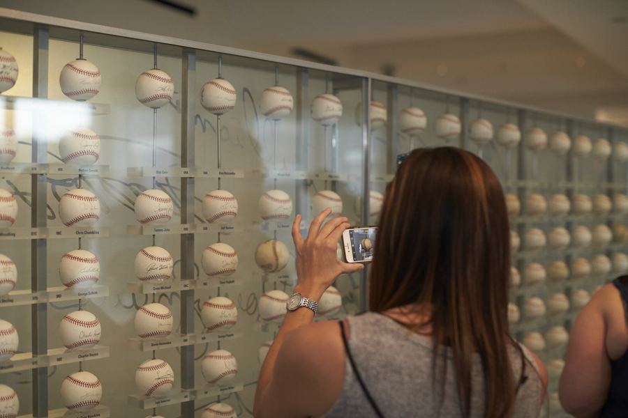 A visitor photographing the wall of signed baseballs in the New York Yankees Museum