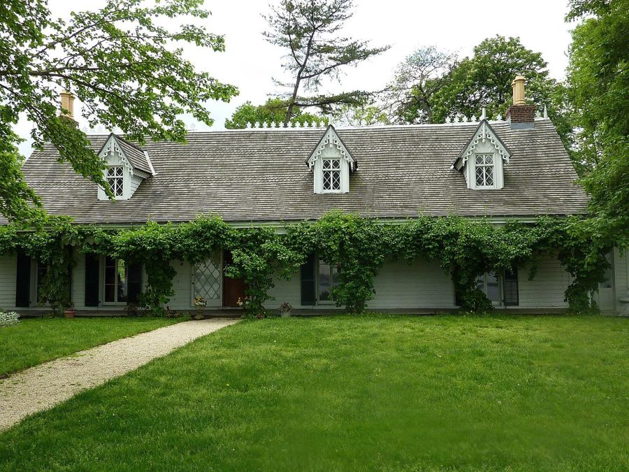 The low, vine-covered Alice Austen House with its white dormers, behind a sloping green lawn