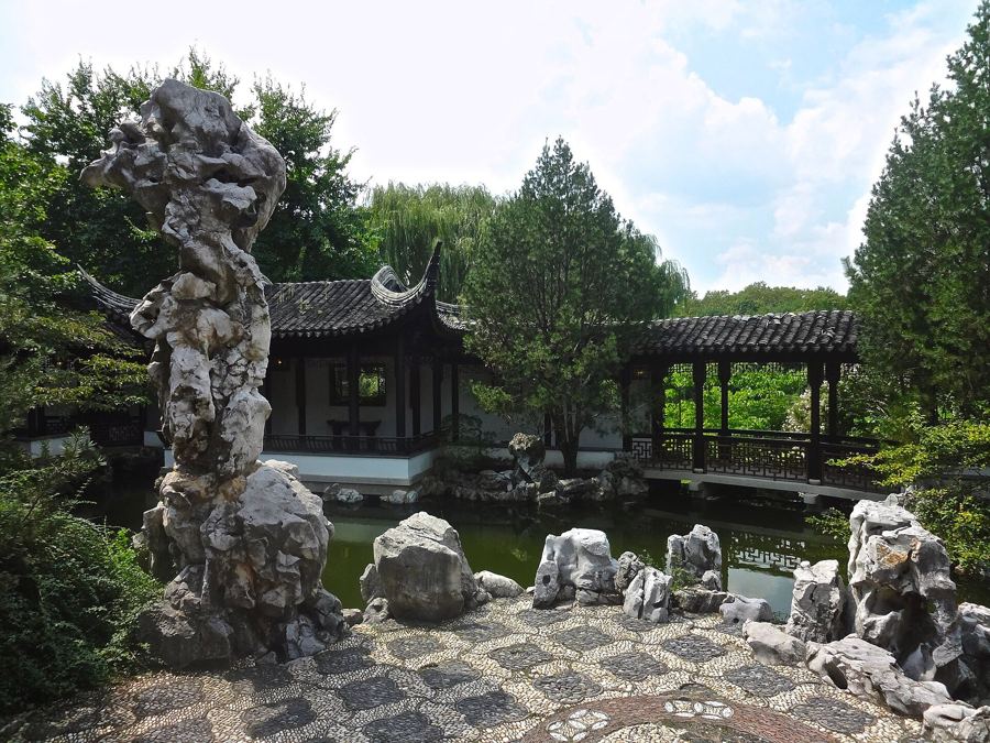 A tall scholar's rock, a pavilion and a pond in the walled New York Chinese Scholar's Garden on Staten Island