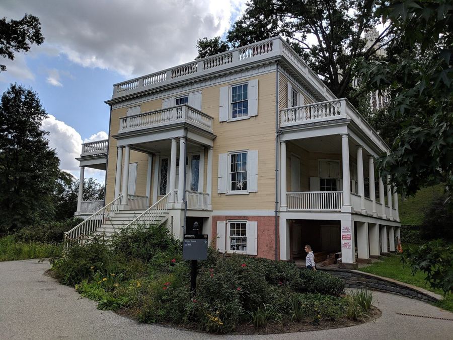 The yellow Federal-style Hamilton Grange with its wraparound porches, set in St. Nicholas Park