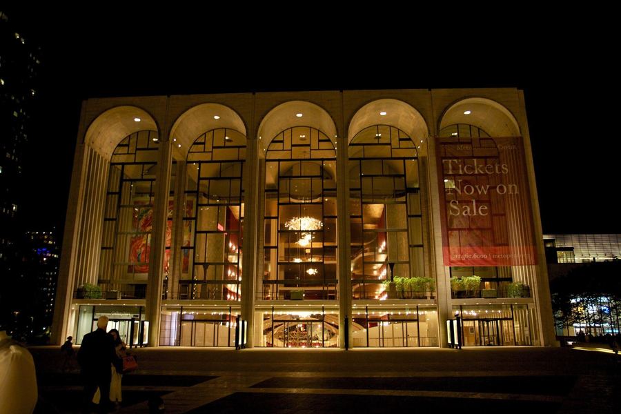 The Metropolitan Opera House at Lincoln Center at night, its arched windows lit from within