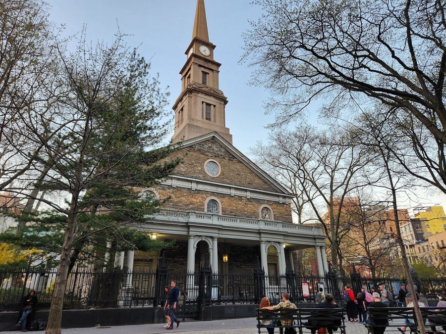 St. Mark's Church in-the-Bowery, home of the Poetry Project, with its steeple and porch behind the churchyard trees
